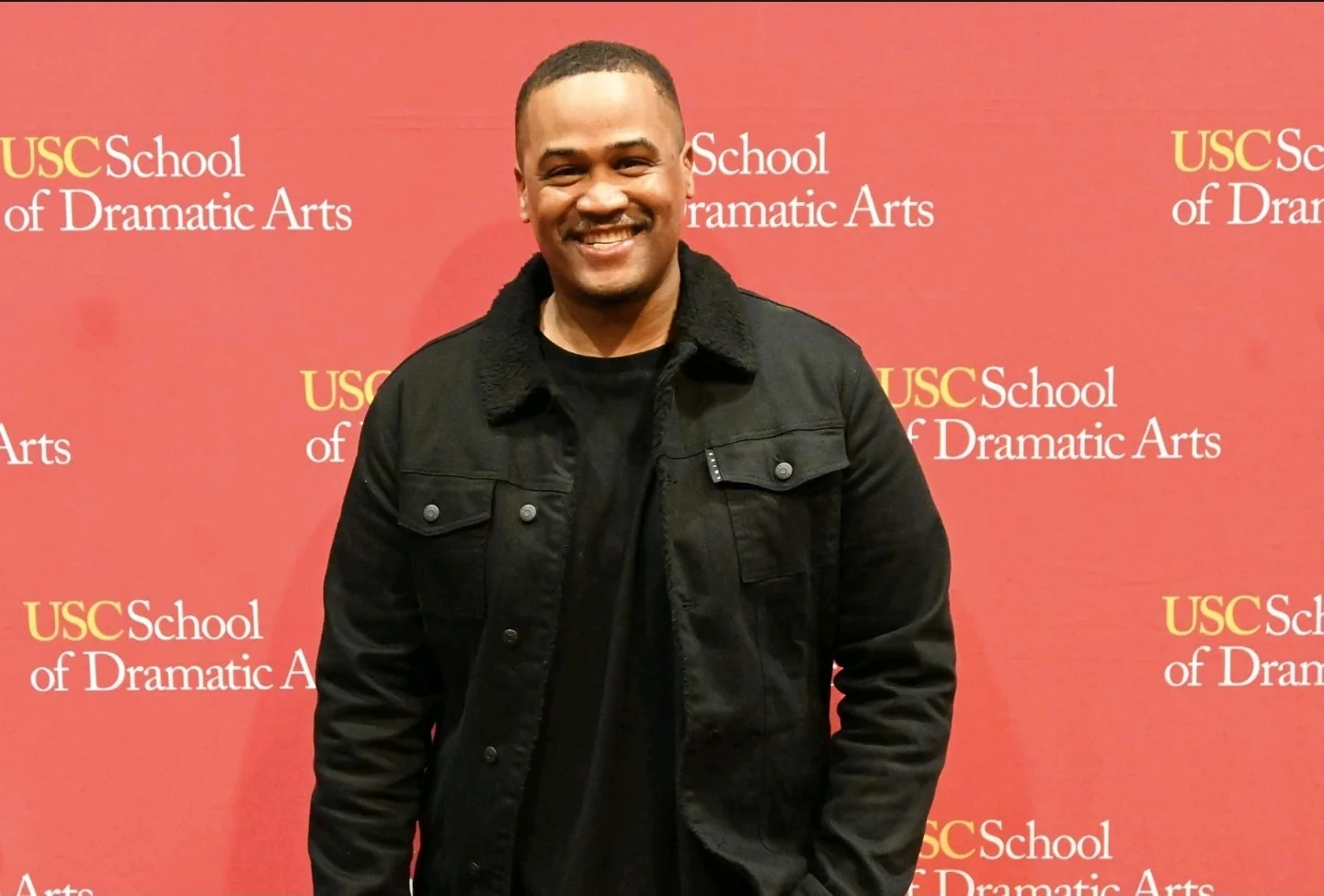 E'Ian West smiling at the USC School of Dramatic Arts event backdrop E'Ian West smiling at the USC School of Dramatic Arts event backdrop