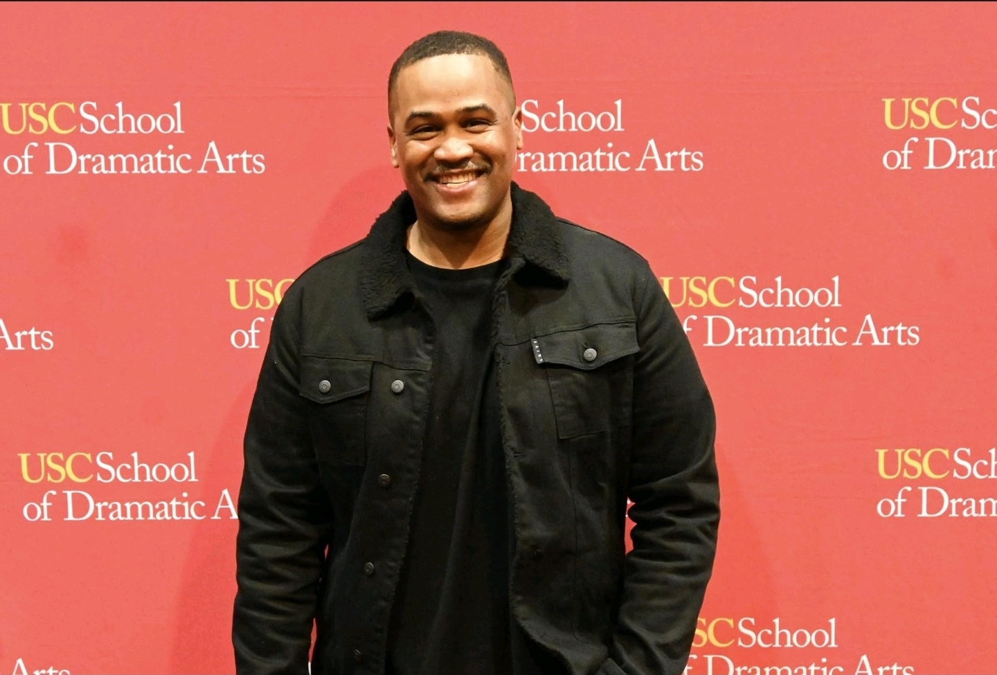 E'Ian West smiling at the USC School of Dramatic Arts event backdrop E'Ian West smiling at the USC School of Dramatic Arts event backdrop